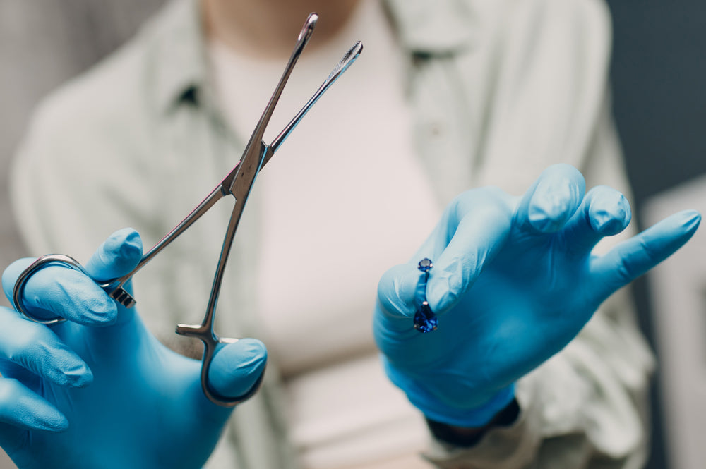 A piercing professional who is showing the type of belly piercing jewellery that she will be using.