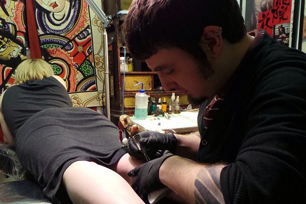 Chris Lambert tattooist, tattooing a female clients leg
