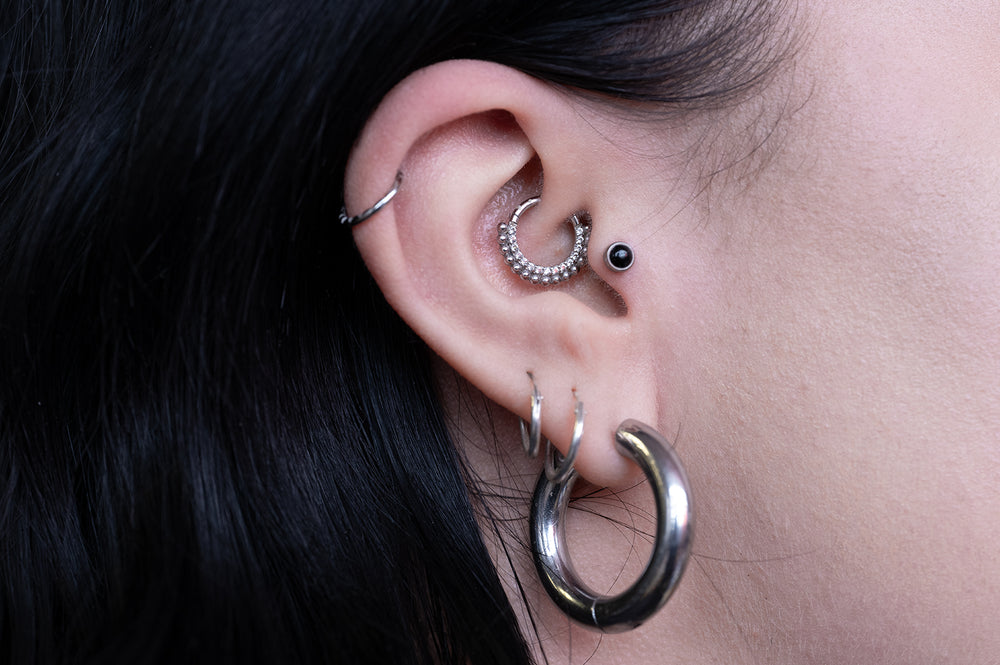 a close up of a women's ear, that showcases multiple ear piercings, including a daith piercing