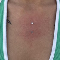 A women wearing a green bikini top, showing her chest dermal piercing in the centre of her chest