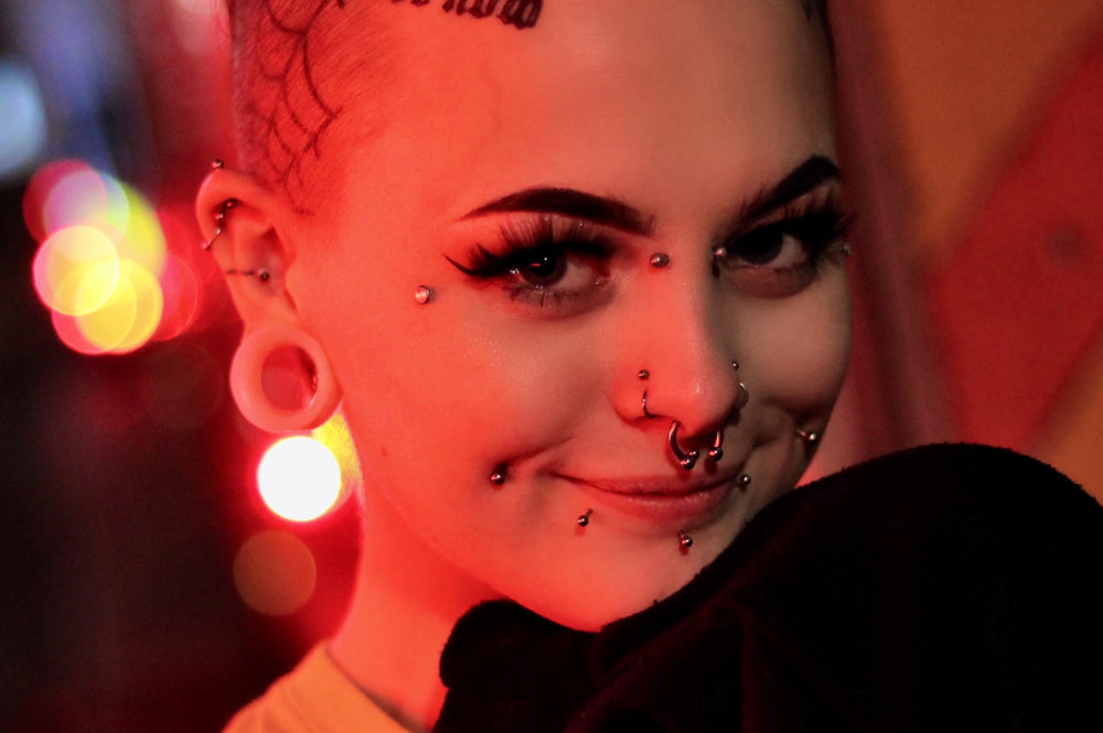 A women happily showing her different types of mouth piercings. 