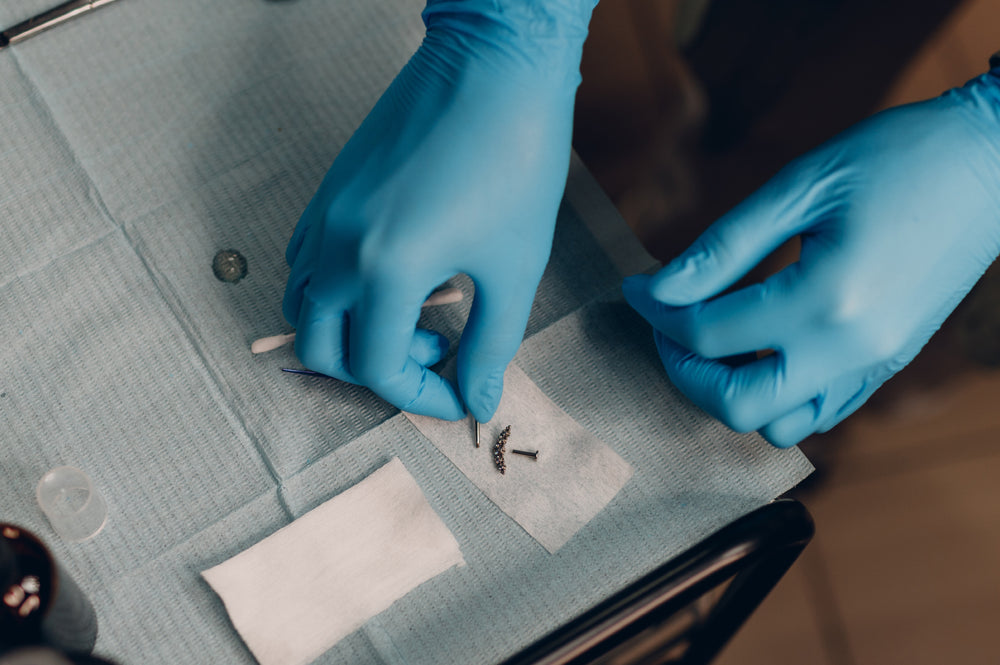 A professional piercer, arranging body piercing jewellery on a sterile table