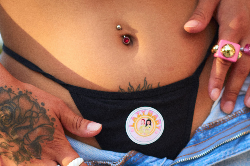 A women showing her fashionable belly button piercing and tattoos in the summer.