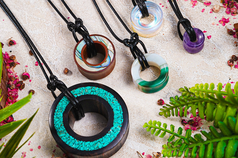 A variety of wood and stone ear tunnels, repurposed on rope necklaces