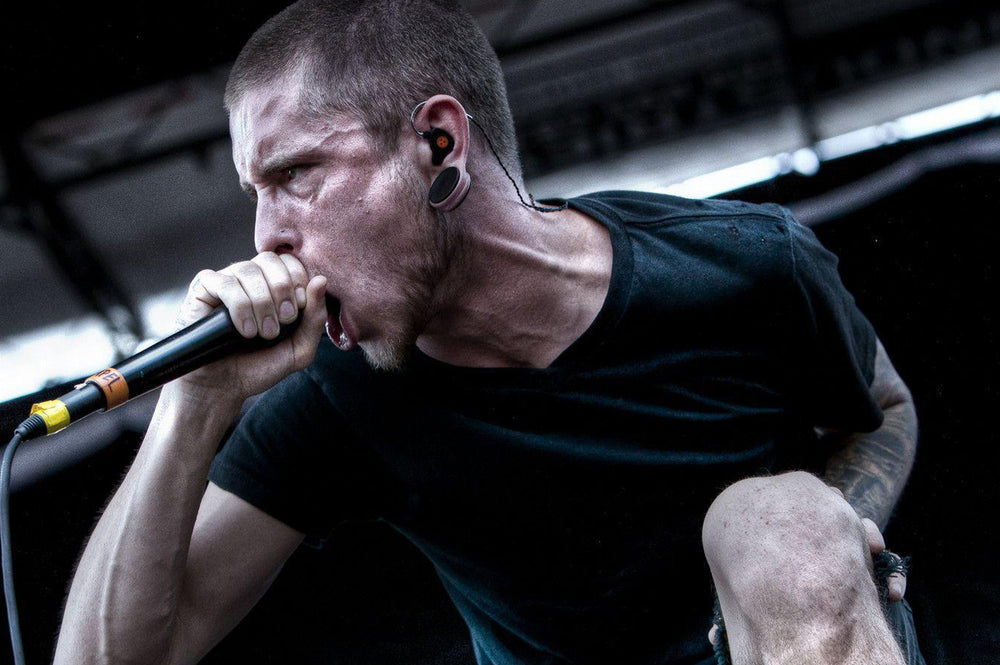a famous male singer singing heavily into a mic, with stretched ears