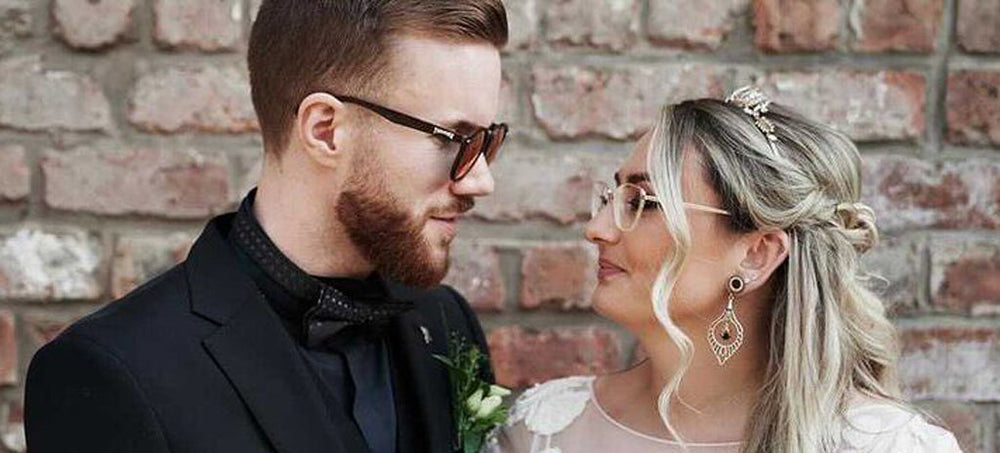 Two People Looking at Eachother on their wedding day with ear stretchers and gauges in their formal wear