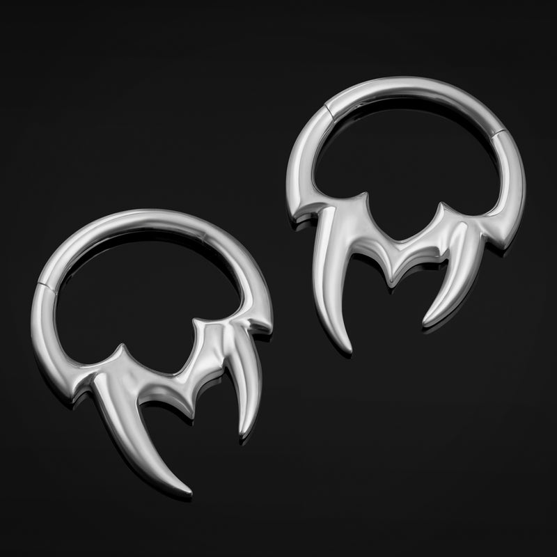 Pair of silver bat-shaped earrings on a black background